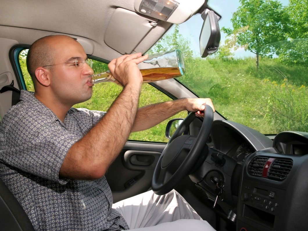man drinking alcohol behind the wheel of his car