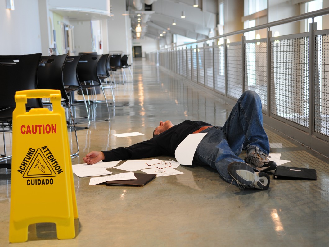 man on the ground with papers all around him next to a yellow caution sign