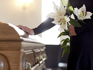 a person placing their hand on a wooden coffin